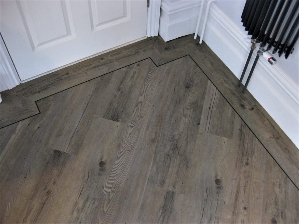 Distinctive LVT detail border work around pipes.